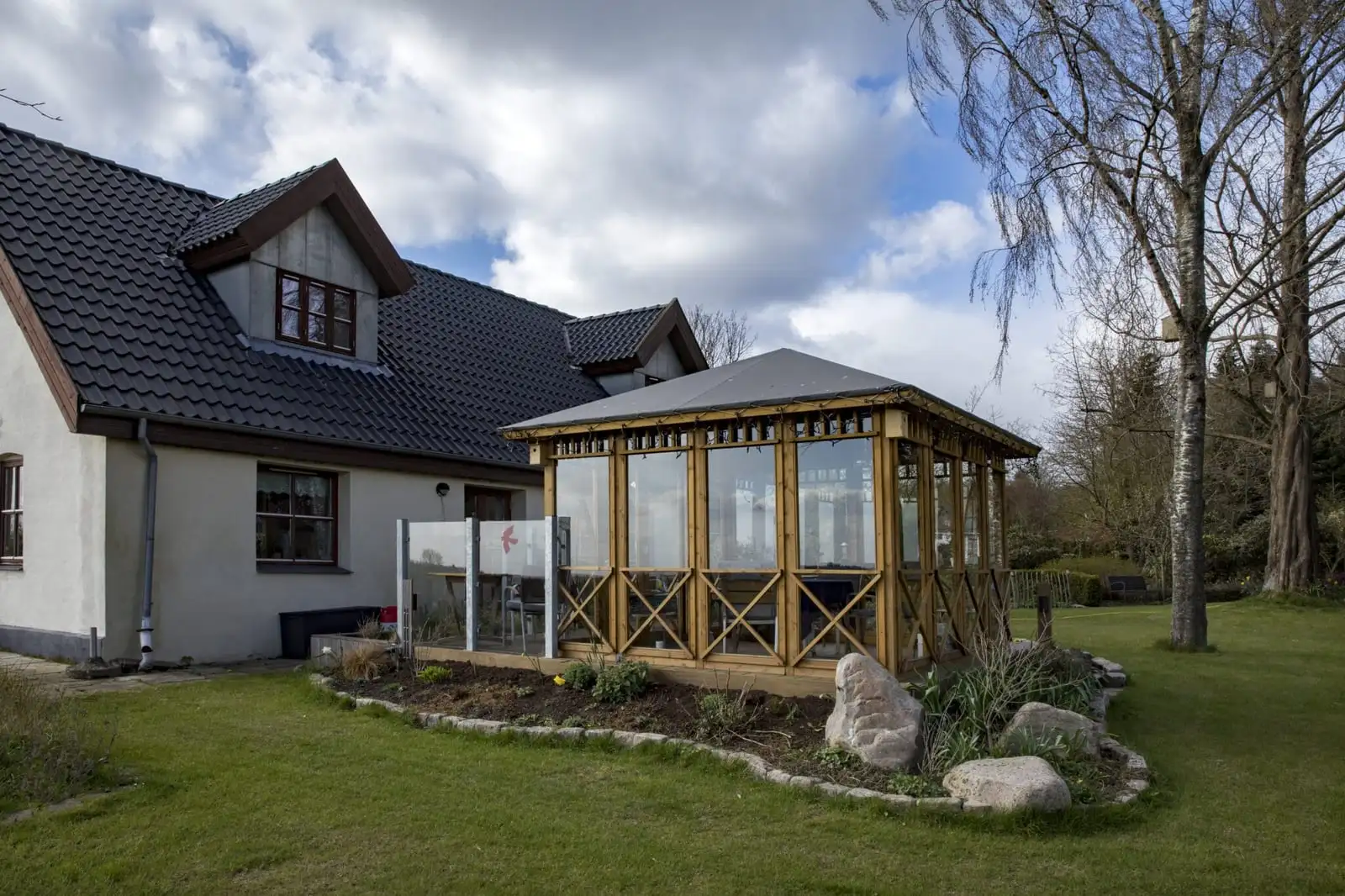 Landhuset med den overdækkede pavillon og haven foran