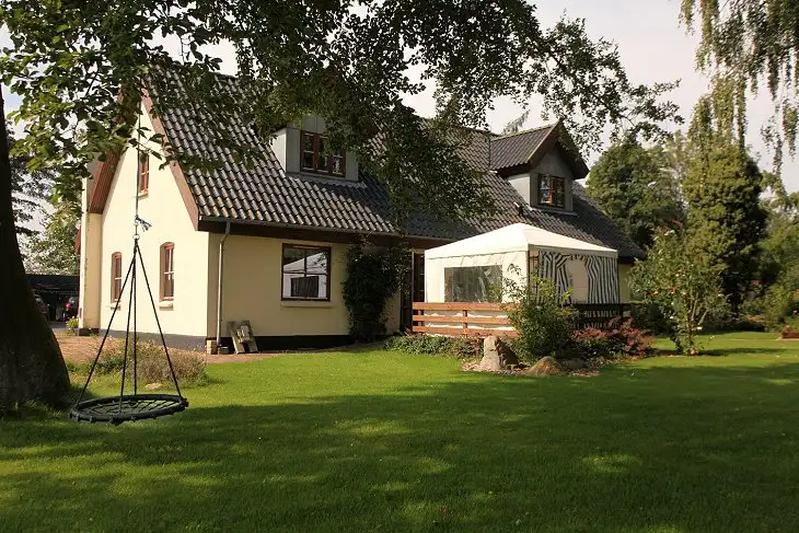 Landhuset set fra haven med gynge og telt