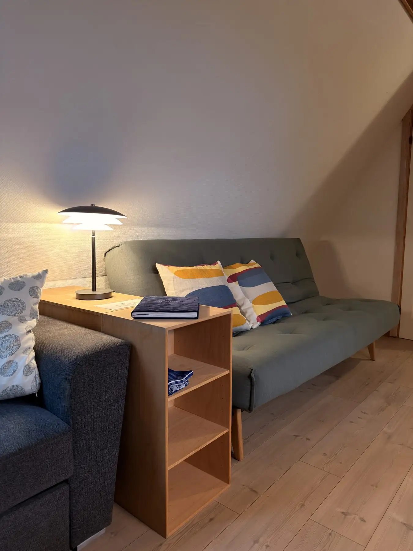 Sovesofa med puder og læselampe i lejlighedens opholdsrum