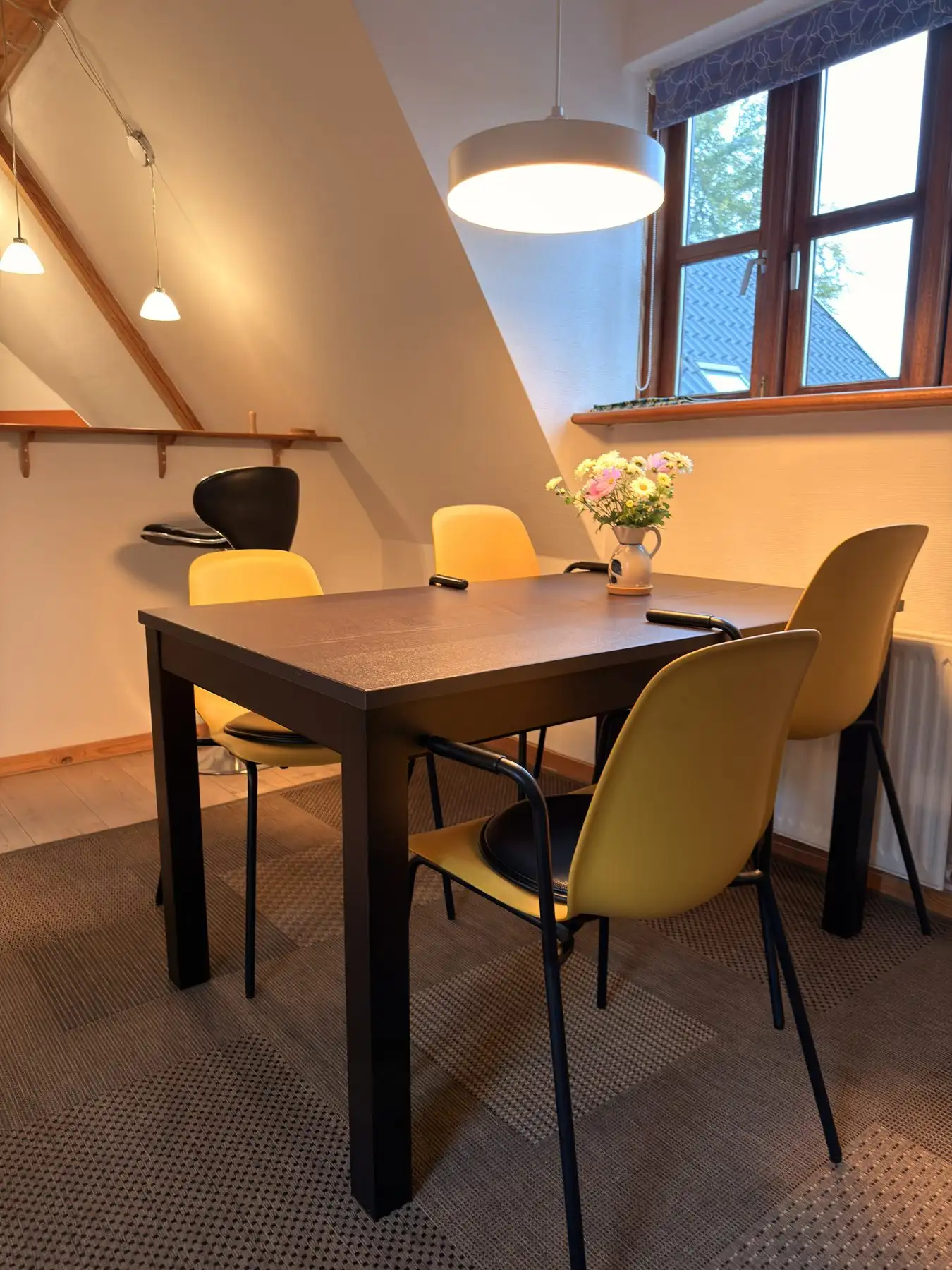 Spisebord med gule stole under vinduet i lejligheden